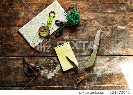 Notepad and pen on the table. Route planning. Knife and rope on the table. Compass and map. Tourist kit. 121672041
