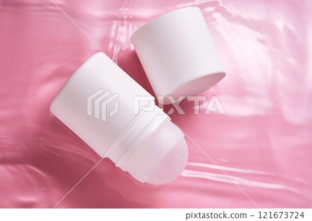 Roll-on deodorant on a pink background in water. 121673724