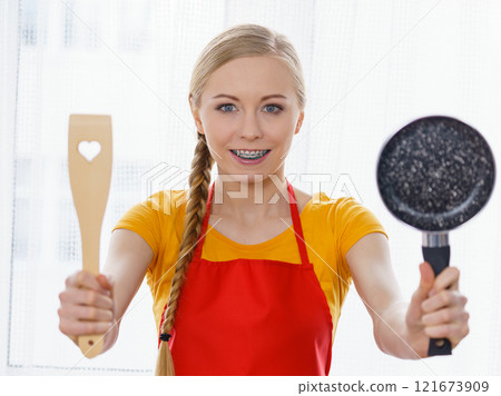 Woman holding cooking pan and spatula 121673909