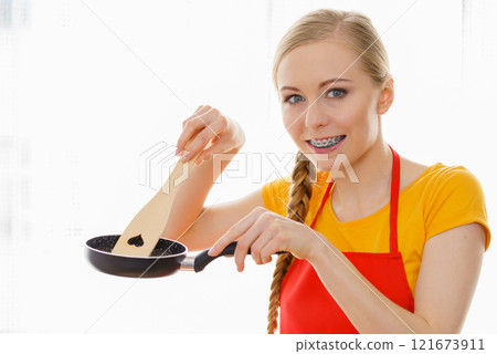 Woman holding cooking pan and spatula 121673911