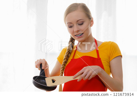 Woman holding cooking pan and spatula 121673914
