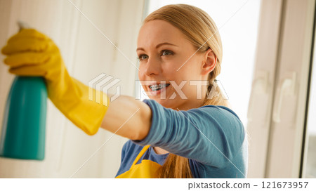 Girl cleaning window at home using detergent rag 121673957