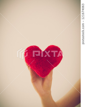 Woman hand holding red small heart 121674063