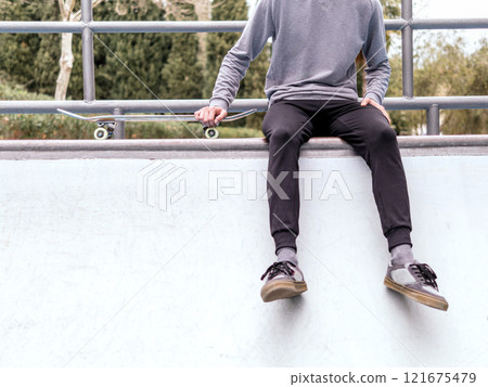 Young Man Sitting with Skateboard at Park Young Man Sitting with Skateboard at Park 121675479
