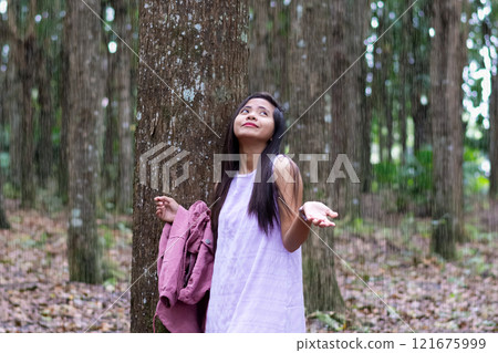 beautiful young asian woman hiding from tropical rain under a tree beautiful young asian woman hiding from tropical rain under a tree 121675999