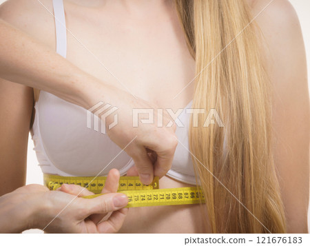 Woman measuring girl under breast 121676183