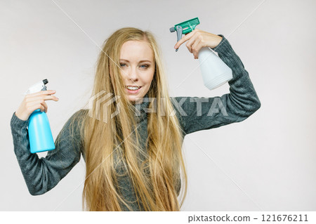 Female messy long hair holds spray bottle 121676211
