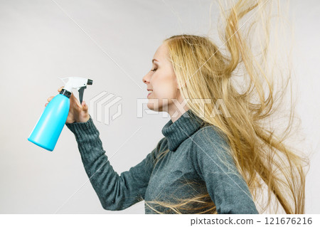 Girl messy hair holding spray bottle 121676216