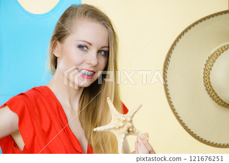 Young woman holding sun hat and starfish Young woman holding sun hat and starfish 121676251