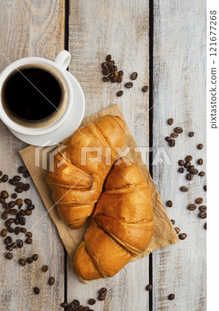 croissant and black coffee in white cup for breakfast. Flat lay. Top view with copy space. Cup and coffee grains. 121677268