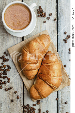 Breakfast with cup of coffee and fresh croissant. Flat lay. Top view. Homemade croissant with black coffee or americano Breakfast with cup of coffee and fresh croissant. Flat lay. Top view. Homemade croissant with black coffee or americano 121677390