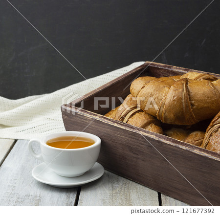 Close-up of croissants on a dark background. Fresh and delicious French pastries, bakery concept, close-up image. tea . Close-up of croissants on a dark background. Fresh and delicious French pastries, bakery concept, close-up image. tea . 121677392