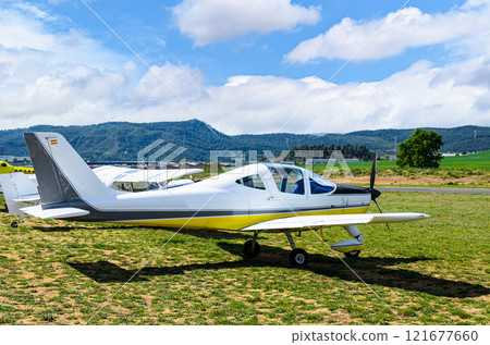 Single engine ultralight airplane waiting to take off at the airfield with blue sky and field background 121677660