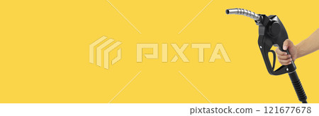 Hands holding Fuel nozzle on yellow background Hands holding Fuel nozzle on yellow background 121677678