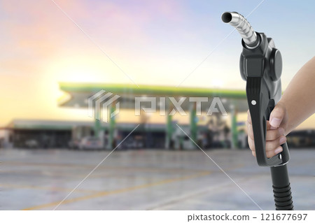 Holding a fuel nozzle against with gas station blurred background 121677697