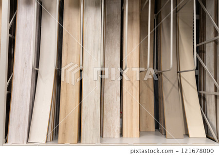 A close-up of various wooden laminate textures and colors displayed on racks in a home improvement store 121678000