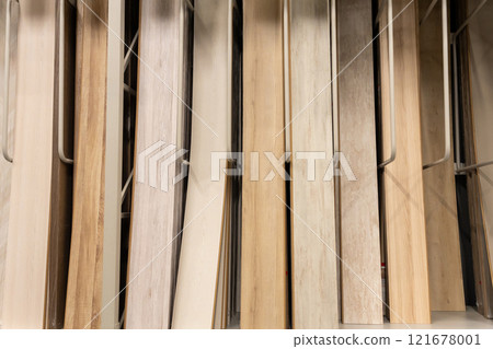 A close-up of various wooden laminate textures and colors displayed on racks in a home improvement store A close-up of various wooden laminate textures and colors displayed on racks in a home improvement store 121678001