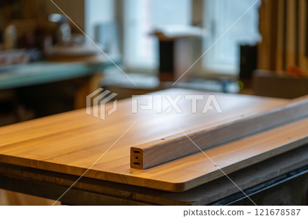 Disassembled wooden table parts in carpentry studio. Legs, base and tabletop, organized for assembly 121678587