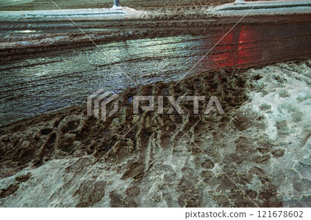 Heavy snowfall followed by thaw, slushy snow and dirt cover roads as salt melt snow into muddy slush 121678602