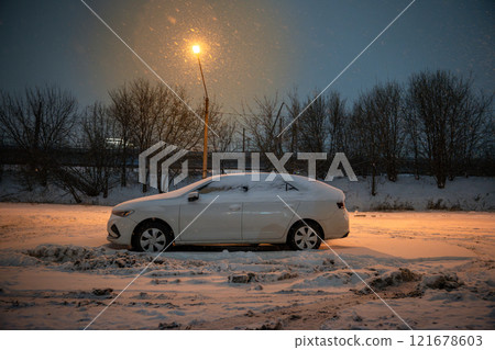 Snowy winter night, car sit on empty parking lot under streetlamp. Engine stalled, frozen streets 121678603