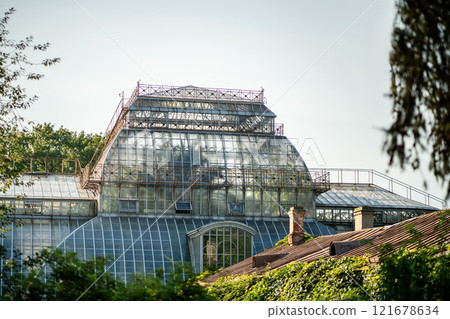 Vintage greenhouse with glass dome and panoramic windows against clear sky. Historical landmark, POI Vintage greenhouse with glass dome and panoramic windows against clear sky. Historical landmark, POI 121678634