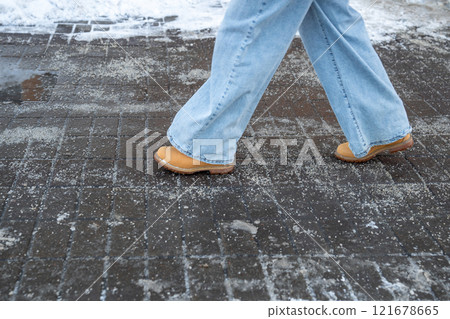 Anti-icing chemicals. Woman walking on the street treated with technical salt or de-icing chemicals Anti-icing chemicals. Woman walking on the street treated with technical salt or de-icing chemicals 121678665