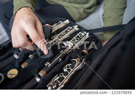 Closeup of musician hands gently wipe clarinet with cloth, removing dust and fingerprints in case 121678695