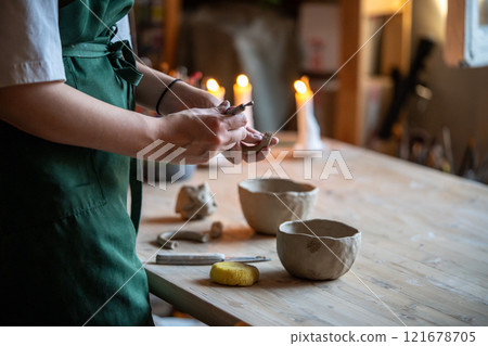 Woman ceramist make pottery cup handle in studio. Creative girl pottery master shaping pot mug Woman ceramist make pottery cup handle in studio. Creative girl pottery master shaping pot mug 121678705