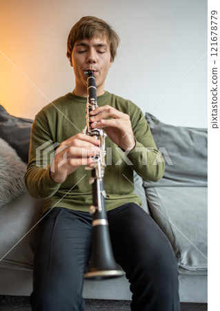 Clarinet player. Clarinetist playing flute woodwind music instrument at home. Guy plays oboe Clarinet player. Clarinetist playing flute woodwind music instrument at home. Guy plays oboe 121678779