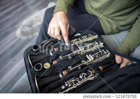 Man carefully places disassembled clarinet into case, wipes parts to remove dust, fingerprints.  121678788