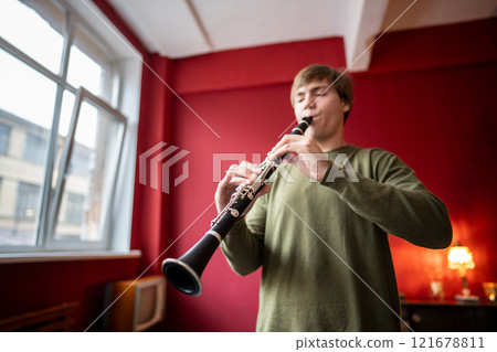 Clarinet player. Clarinetist hands playing flute woodwind music instrument at home. Guy plays oboe 121678811