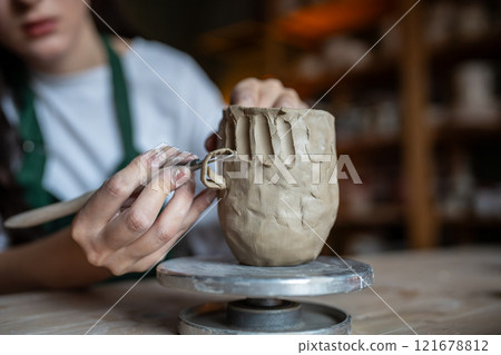 Ceramics creation process. Female artist shaping and sculpting clay pottery. Working table in studio Ceramics creation process. Female artist shaping and sculpting clay pottery. Working table in studio 121678812