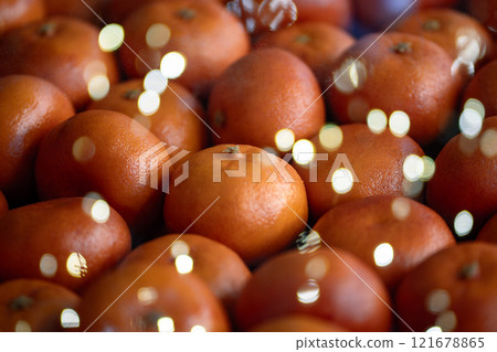 Ripe tangerines behind glass of the store with reflection of Christmas garland lights on showcase. 121678865