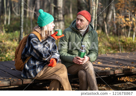 Relaxed man, woman relaxing in autumn forest, drink tea, communicate, spend quiet nice time together 121678867