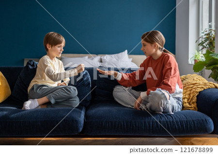 Two kids boy and girl friends play rock paper scissors while sitting on sofa at home 121678899