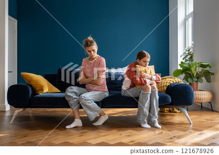 Upset frustrated mother and teenage daughter ignoring each other after quarrel at home, not talking Upset frustrated mother and teenage daughter ignoring each other after quarrel at home, not talking 121678926
