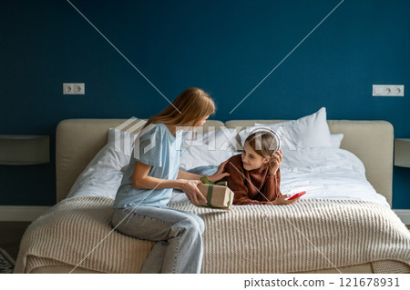 Caring attentive woman mother congratulate beloved teen daughter with birthday give present box gift Caring attentive woman mother congratulate beloved teen daughter with birthday give present box gift 121678931