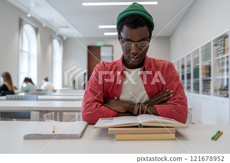 Study concentrated mixed race student male prepares for important college library scholarship test 121678952