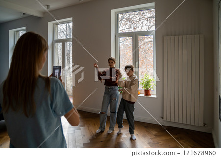 Mother holding smartphone helping kids to record funny dance video for social media 121678960
