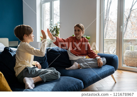 Older sister spending time with younger brother at home 121678967