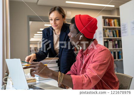 Couple multiethnic pleased students working as team on research project in library for scholarship. 121678976