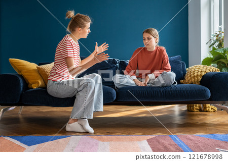 Upset annoyed parent mom talking arguing with teen girl daughter sitting on couch at home. Upset annoyed parent mom talking arguing with teen girl daughter sitting on couch at home. 121678998