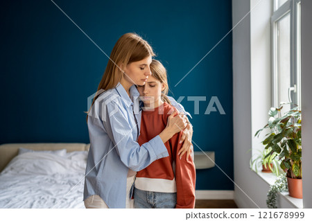 Affectionate empathic young mom tender embracing calming sad upset teen daughter. Affectionate empathic young mom tender embracing calming sad upset teen daughter. 121678999