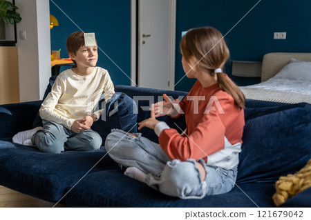 Siblings brother and sister spending leisure time together at home, playing guessing game Who Am I 121679042