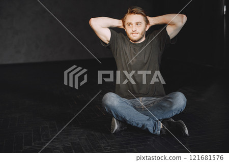 Young man in agony having problems with narcotics. Sad young man sitting in the darkness. Hands above the head. 121681576