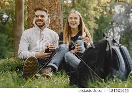 Tourists in a summer forest. Girl in a black t-shirt. Man use a phone. 121681663