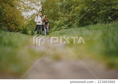 Tourists in a summer forest. Girl in a black t-shirt. Man use a phone. 121681668