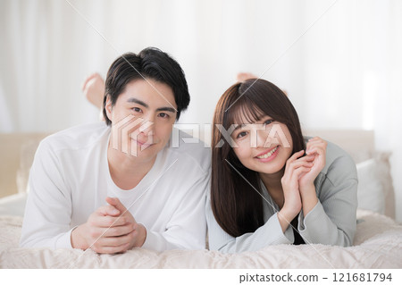 一對微笑的夫婦看著鏡頭在臥室放鬆 一對微笑的夫婦看著鏡頭在臥室放鬆 121681794