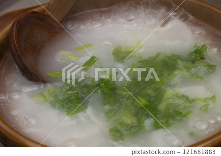 Nanakusa-gayu (rice porridge with seven herbs) Cooking nanakusa-gayu (rice porridge with seven herbs) cooked in a clay pot - cooking scene Nanakusa-gayu (rice porridge with seven herbs) Cooking nanakusa-gayu (rice porridge with seven herbs) cooked in a clay pot - cooking scene 121681883