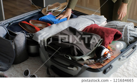 Young woman arranges clothing in suitcase, preparing for an upcoming business trip or weekend adventure Young woman arranges clothing in suitcase, preparing for an upcoming business trip or weekend adventure 121684665